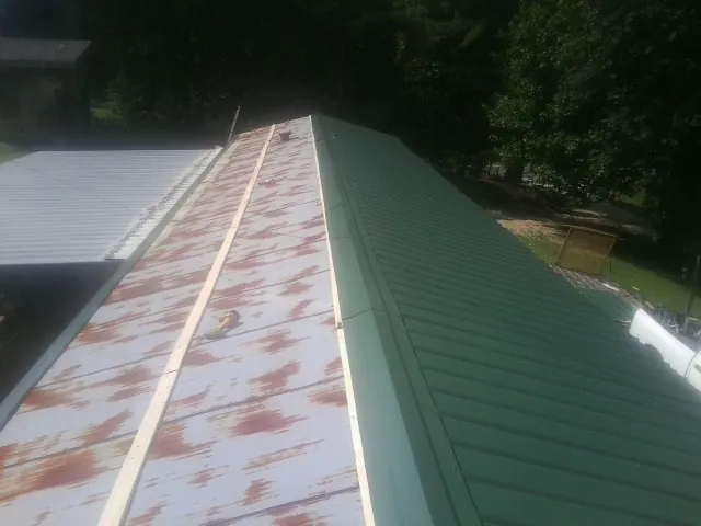 Old rusted panels beside newly installed green metal roofing — Wind Damage Roof Repair by Roofing Brothers in Palmer