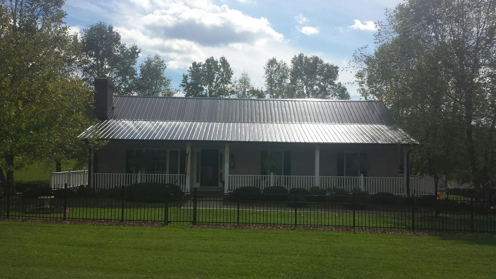 Gray metal roof on a brick ranch with a full width front porch — Gutter Guard Installation work by our crew in Palmer